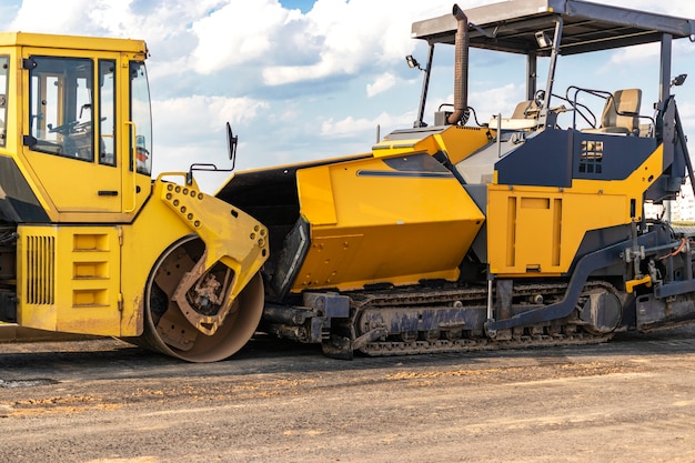 Asphalt paving equipment. Asphalt paver and heavy vibratory roller.