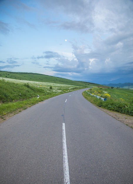 Asphalt road goes down the mountainside in the evening