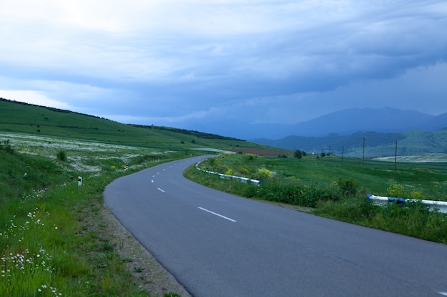 An asphalt road goes through the fields in the evening