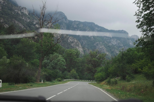 Asphalt road goes through forests and mountains