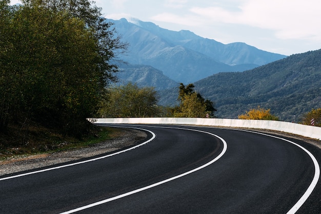 Asphalt road. Paved road on the background of mountains. Road on the background of beautiful mountains in the Caucasus. Landscapes of the country. Journey through beautiful places by car. Copy space