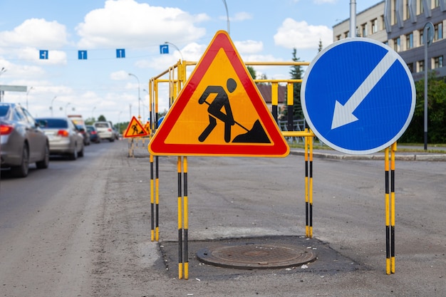 Asphalt road repairs yellow warning triangle signs about road works and bypass directions