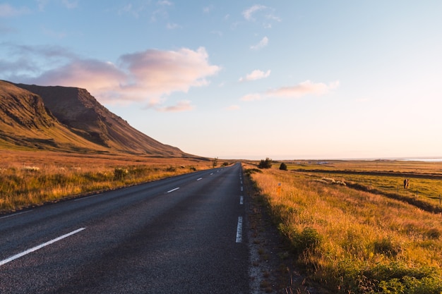 Asphalt road on a sunny day in Iceland with a hill 