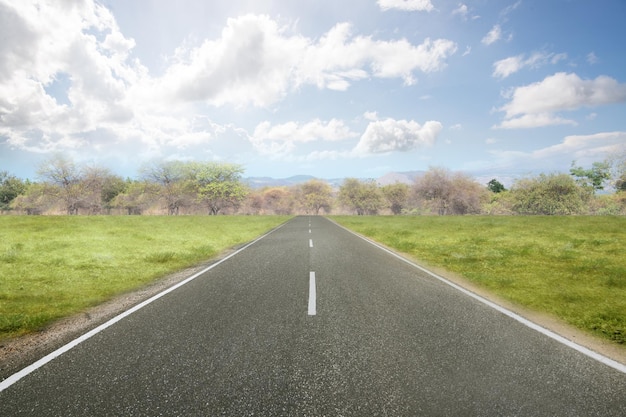 Asphalt road with green grass and blue sky background