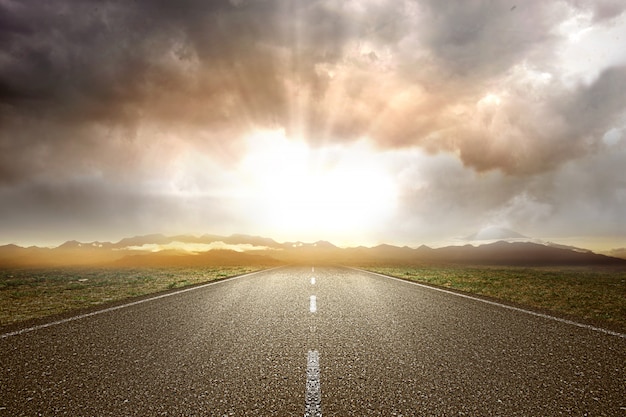 Asphalt road with green grass and mountain view