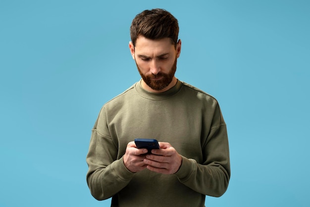 Assertive bearded man attentively looking at display of smartphone he holding