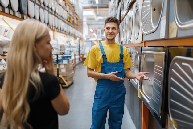 Assistant and female buyer in hardware store. Seller in uniform and woman in diy shop, shopping in building supermarket