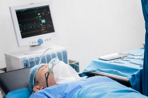 Assistant surgeon put the patient on a ventilatoroxygen mask in preparation for surgery