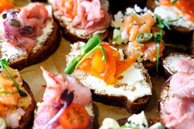 Assorted bruschettas on a wooden tray Fish meat vegetables and herbs Appetizing snacks Closeup