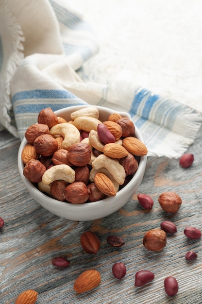 Assorted cashew nuts almonds hazelnuts and peanuts In a white cup Closeup View from above Gray background