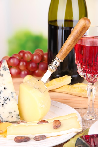 Assorted cheese plate grape and wine glass on table on light background