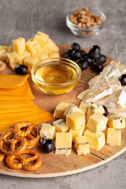 Assorted cheese on a wooden plate on a gray background