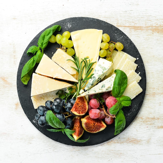 Assorted cheeses on a plate Parmesan cheese blue cheese and brie on a plate with grapes and figs Antipasto Top view