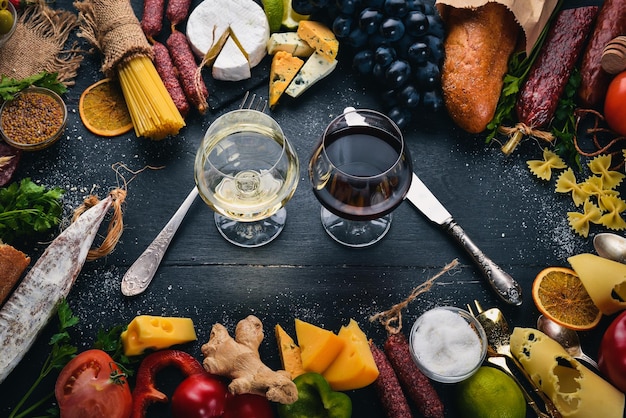 Assorted cheeses sausages wines traditional spices and fresh vegetables on a wooden background Cheese brie blue cheese gorgonzola fuete salami Italian and Spanish Cuisine Free space