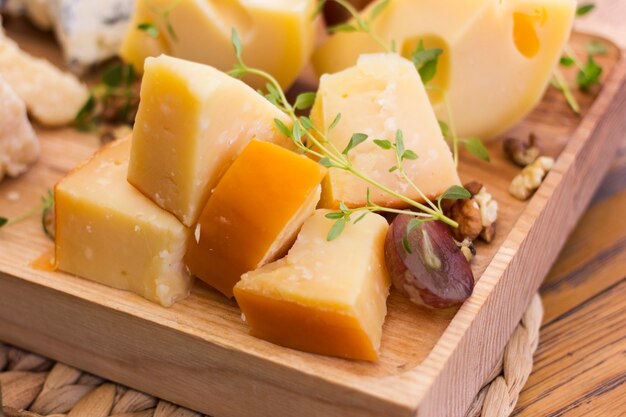 Assorted cheeses with berries, nuts and greens on a wooden tray