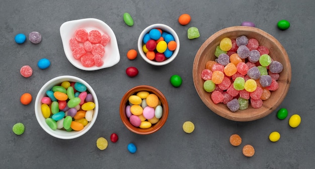 Assorted colorful candies in bowls over stone background