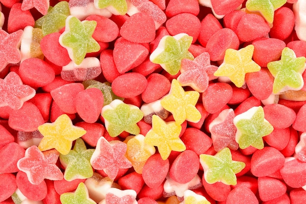 Assorted colorful gummy candies and lollipop on red background. Top view. Jelly  sweets.