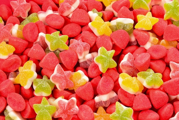 Assorted colorful gummy candies and lollipop on red background Top view Jelly sweets