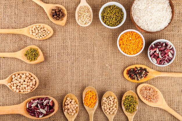 Assorted grain, beans, legumes, peas, lentils in spoons on a burlap background