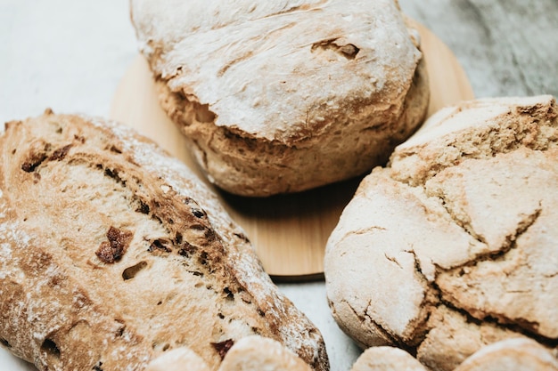 Assorted homemade bread on white clean wood backgroundFresh tasty breadBakery rustic crusty loaves of bread and bunsHomemade natural breads Different kinds of fresh bread as background