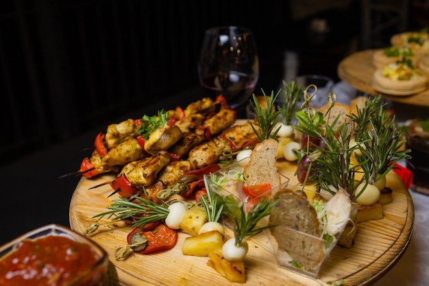 Assorted meat on a plate close up. Different types of meat and potatoes in a heap. Appetizer on a large plate with sauces.