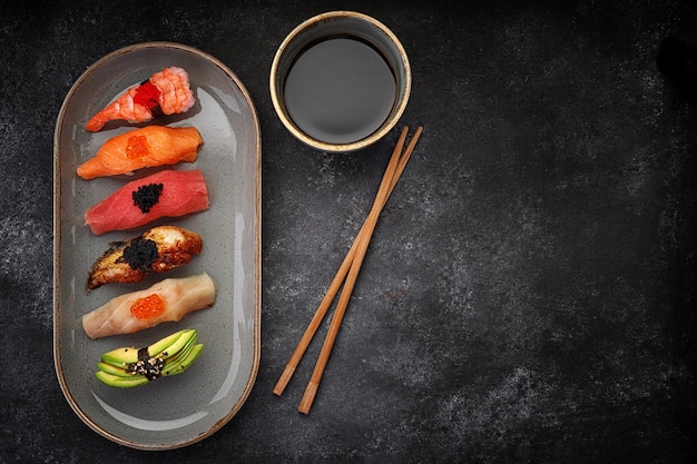 Assorted Nigiri sushi on a plate on dark concrete