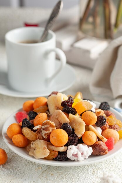 Assorted nuts dried fruits and candied fruit In a white plate Closeup Light background