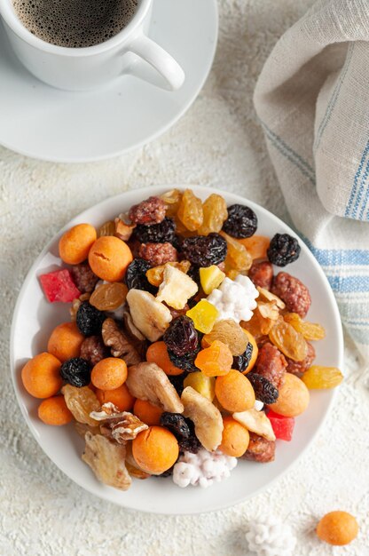 Assorted nuts dried fruits and candied fruit In a white plate Light background View from above