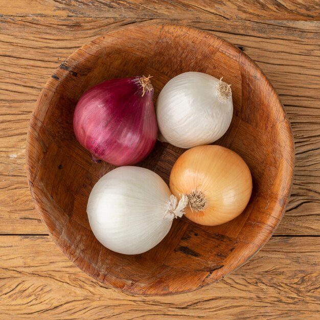 Assorted onions in a bowl over wooden table.