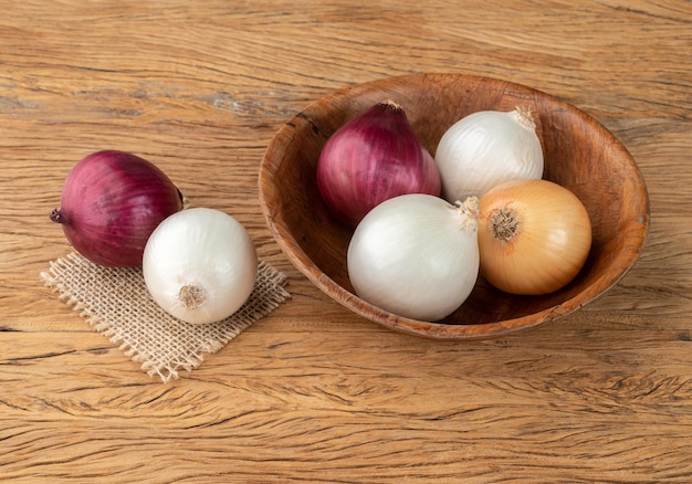 Assorted onions in a bowl over wooden table