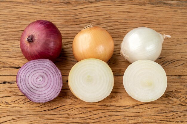 Assorted onions with halves over wooden table.