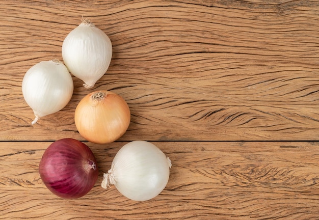 Assorted onions over wooden table with copy space