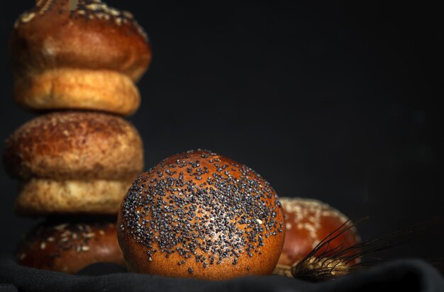 Assorted round homemade brioche buns with seeds on dark background with high contrast light. Isolated