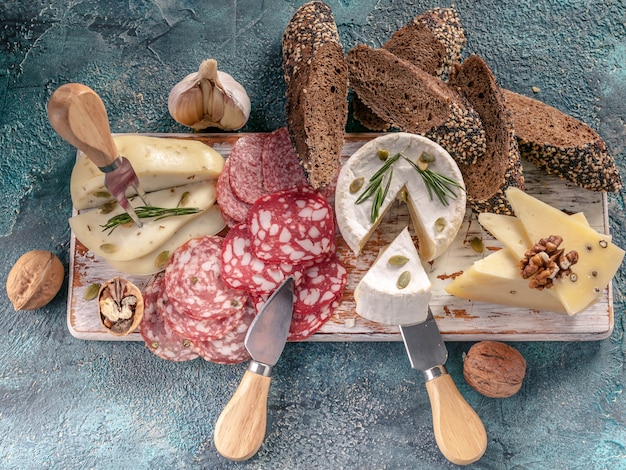 Assorted sausages and cheese with bread on wooden board