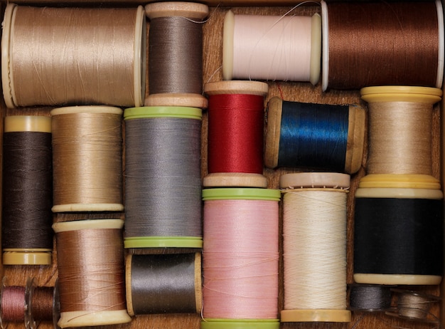 Assorted sewing thread on a wooden background