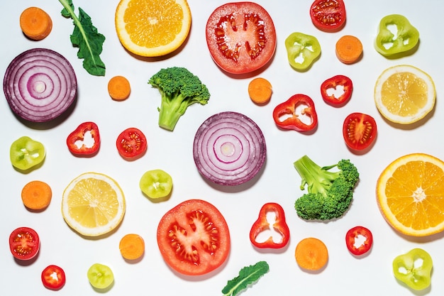 Assorted sliced vegetables and fruits on white surface.