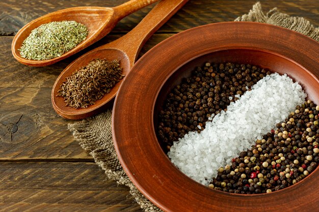 Assorted spices in a plate, spoons and bowls on wooden background.