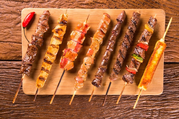 Assorted steak skewers on top of a board