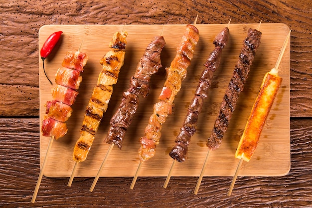 Assorted steak skewers on top of a board