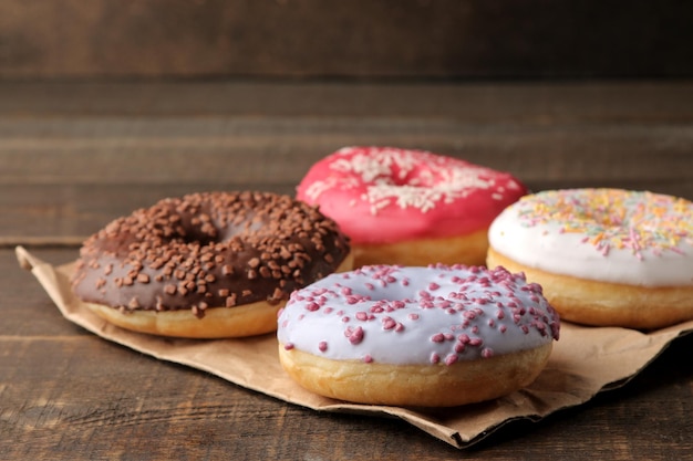 Assorted sweet donuts with icing and sprinkles on a brown wooden table