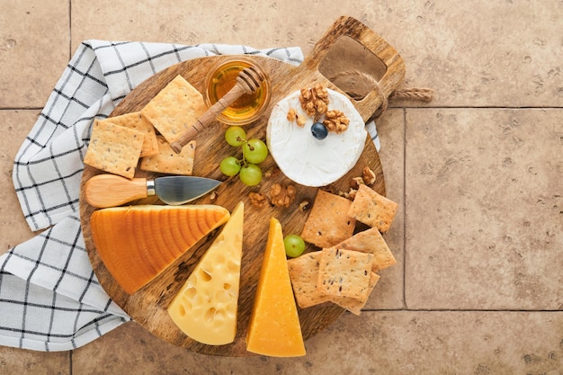 Assortment of cheese honey cracker blueberries grapes with red and white wine in glasses antipasto server on white marble board on grey background Cheese plate Flat lay copy space