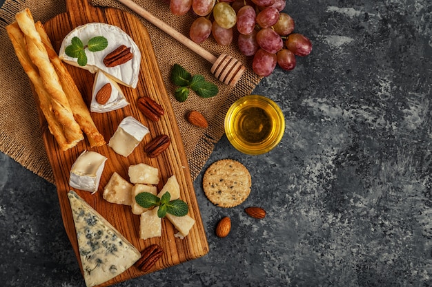 Assortment of cheese with honey and nuts on a cutting board