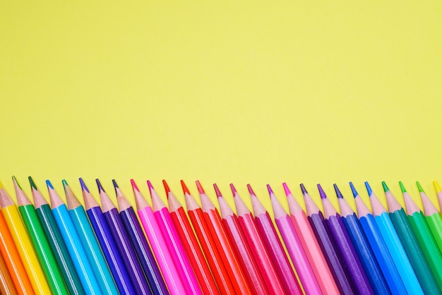 Assortment of colored pencils in various iridescent colors on a yellow