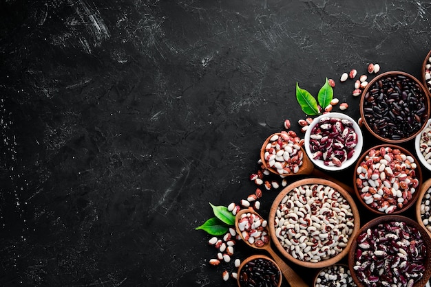 Assortment of colored raw beans On a black stone table Top view Free copy space