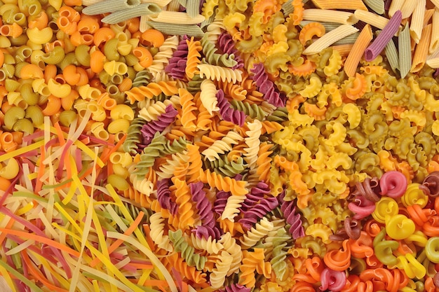 Assortment of colored uncooked Italian pasta as background texture