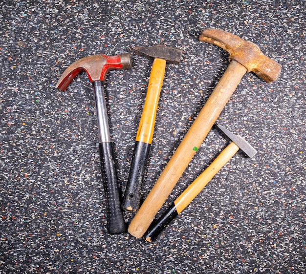 Assortment of different old and used hammers on a dark colorful background