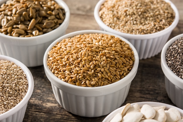 Assortment of different seeds in bowl on wooden table Pumpkin, linen, chia, sunflower, and sesame seeds