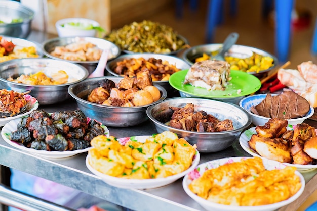 Assortment of Exotic grilled and baked asian food from meat in Hanoi in Vietnam. Street market with Vietnamese cousine. Plates with food on dispay.