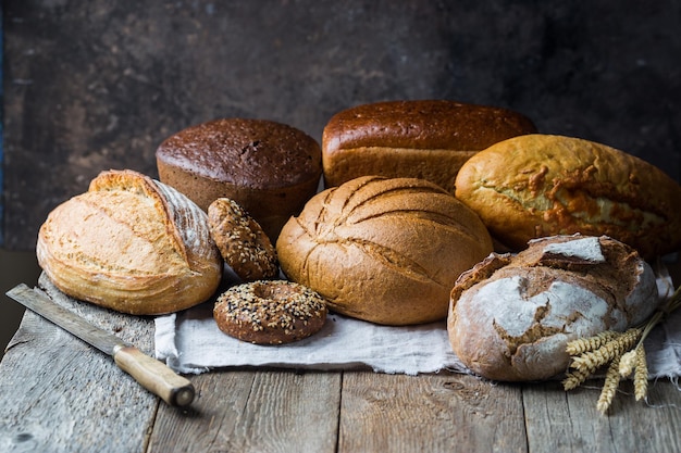 Assortment of fresh baked bread and buns on wooden table background