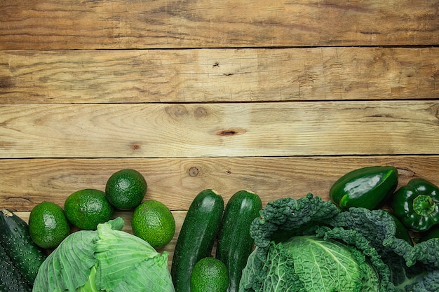 Assortment of Green Vegetables Arranged in Bottom Border on Plank Wood Background.